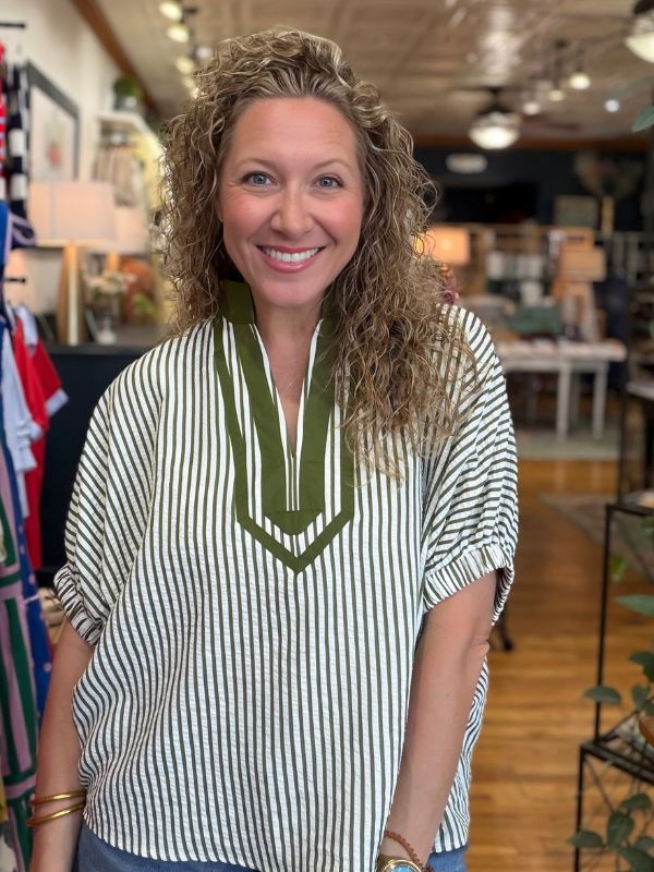 Woman wearing a striped shirt with a green accent in an indoor setting