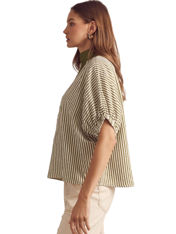 Woman wearing a striped shirt and white pants on a plain background