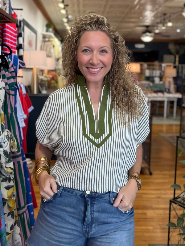 Woman wearing a striped shirt with a green accent in a store setting