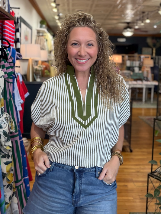 Woman wearing a striped shirt with a green accent in a store setting