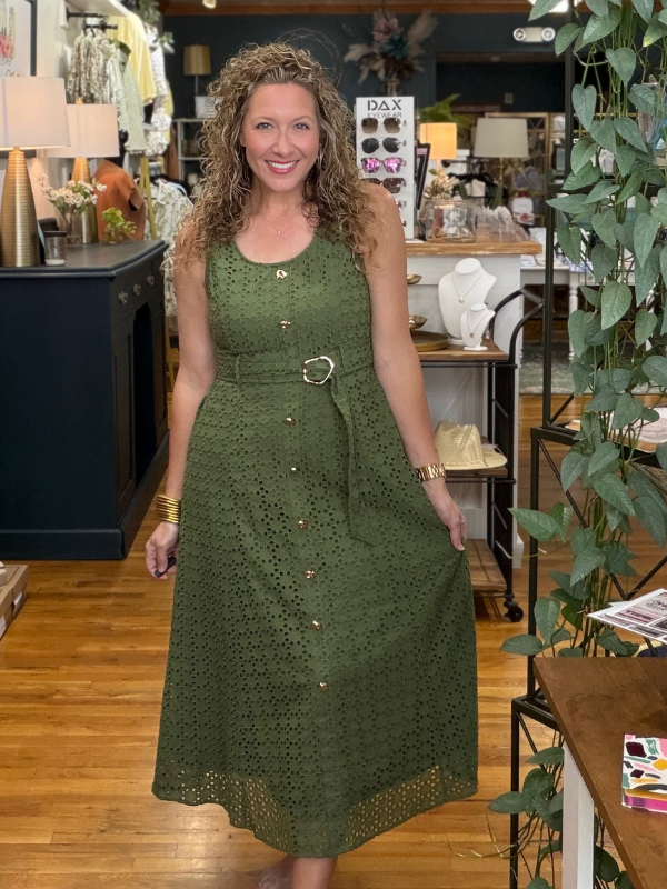 Woman in a green dress standing in a store with various items and decor around her.