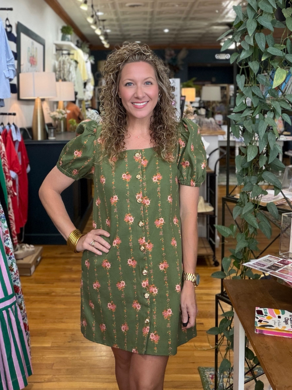 Woman wearing a green floral dress in a store setting