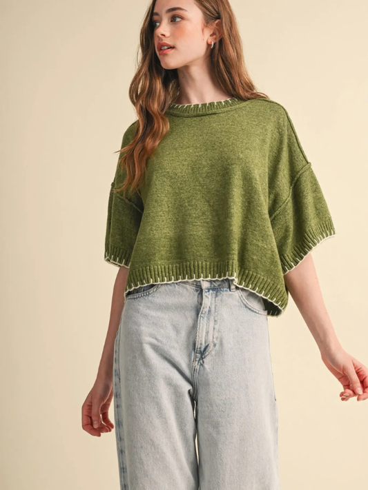 woman wearing an olive stitch sweater and denim jeans