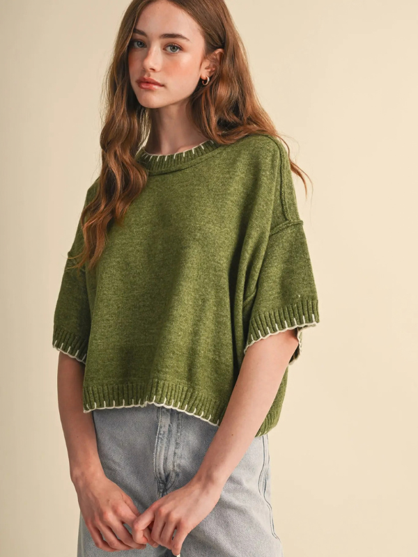 woman wearing an olive stitch sweater and denim jeans