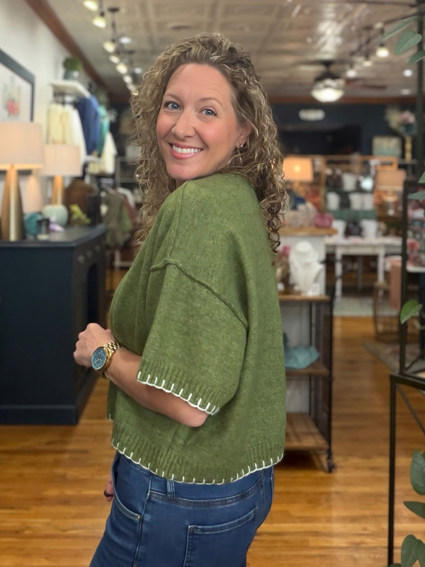 woman wearing an olive stitch sweater and denim jeans