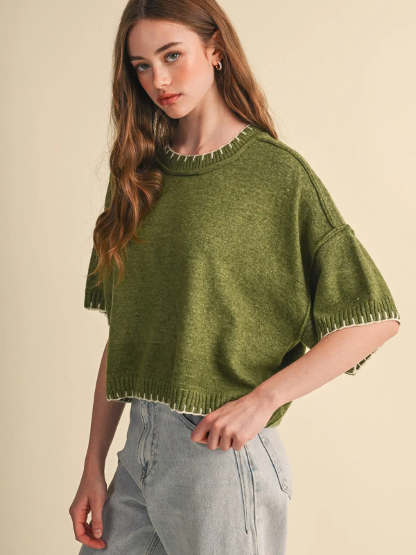 woman wearing an olive stitch sweater and denim jeans