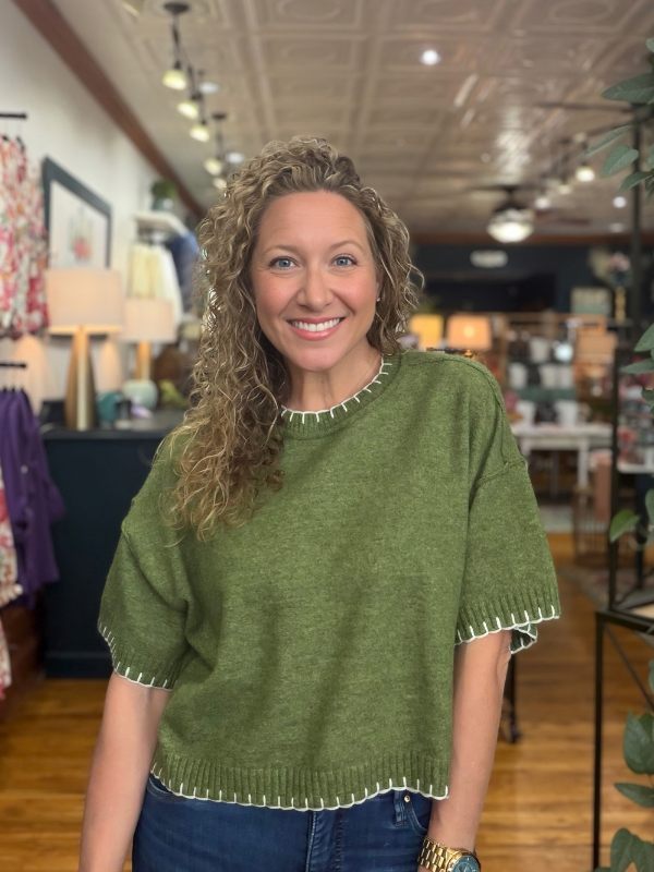 woman wearing an olive stitch sweater and denim jeans