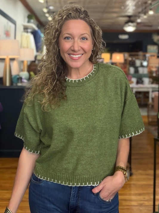 woman wearing an olive stitch sweater and denim jeans