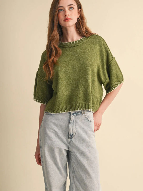 woman wearing an olive stitch sweater and denim jeans