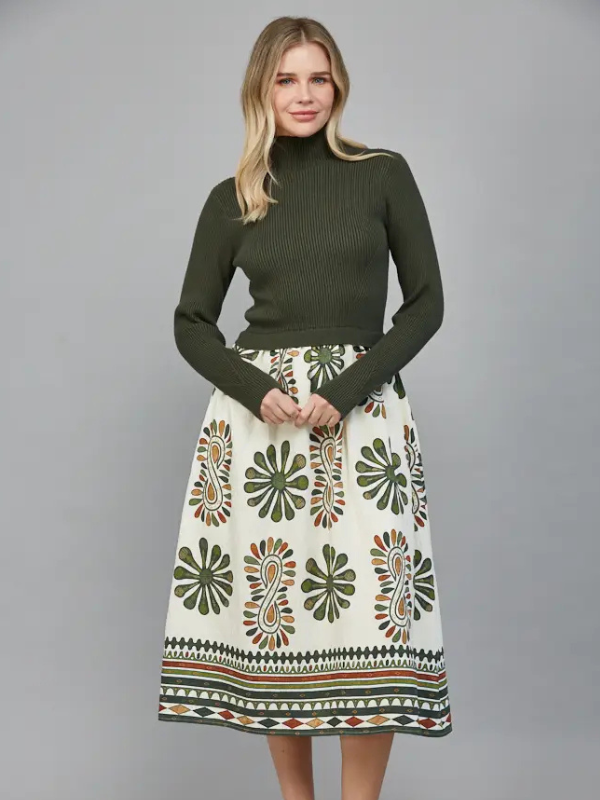 Woman wearing a green turtleneck sweater and patterned skirt on a gray background