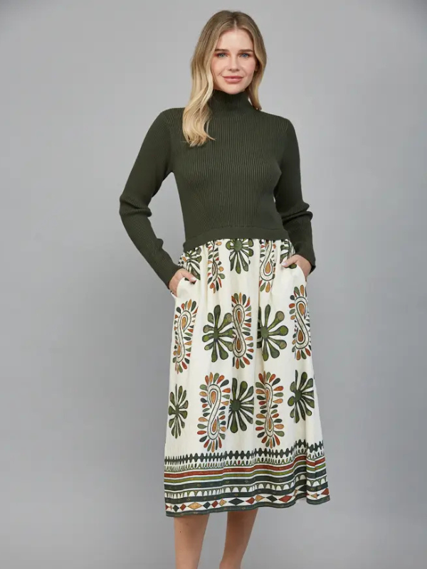 Woman wearing a green turtleneck sweater and patterned skirt on a gray background
