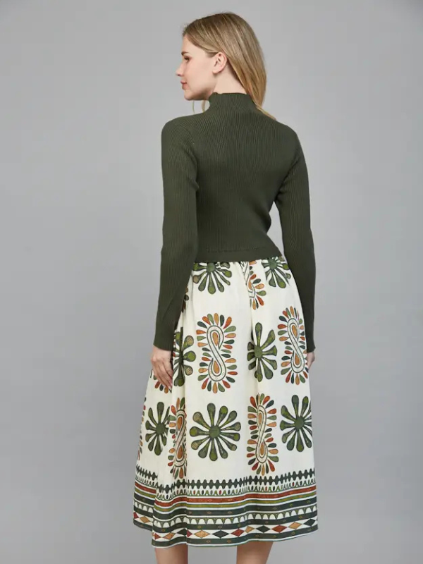 Woman wearing a green turtleneck and patterned skirt on a gray background