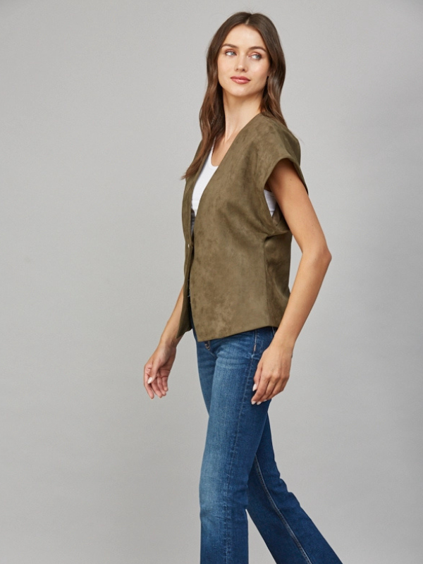 Woman wearing a green suede jacket and blue jeans on a gray background