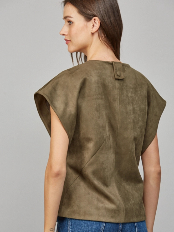 Woman wearing a green suede vest against a gray background