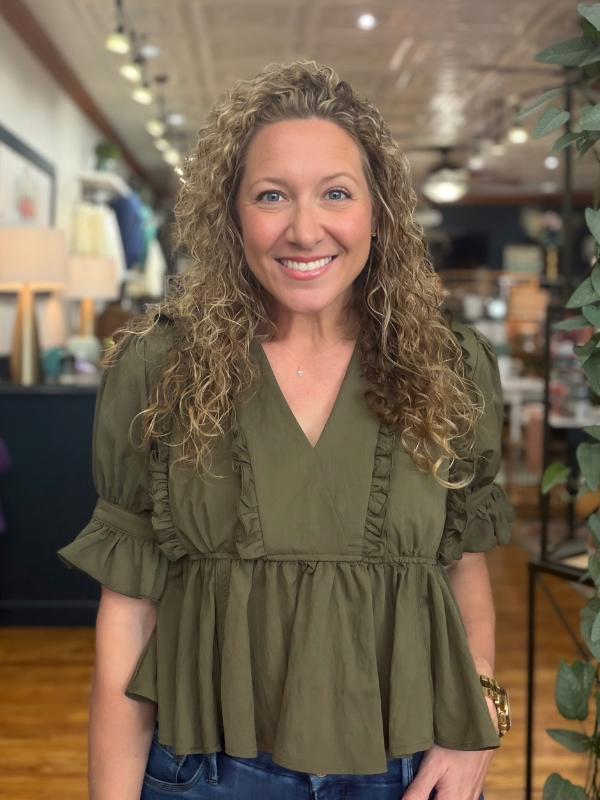 woman wearing an olive  ruffle blouse and jeans 