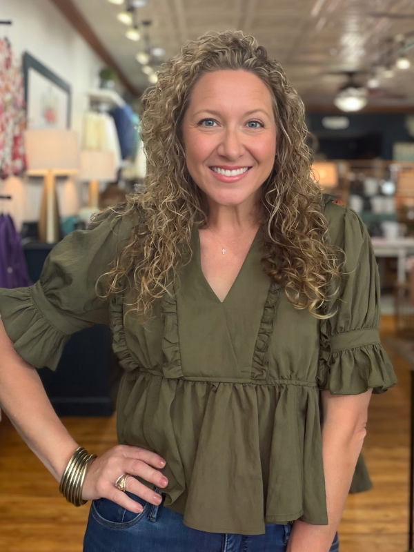 woman wearing an olive  ruffle blouse and jeans 