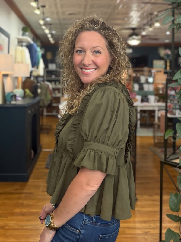 woman wearing an olive  ruffle blouse and jeans 