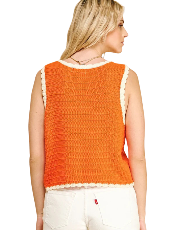 Woman wearing an orange crochet top with white trim on a white background