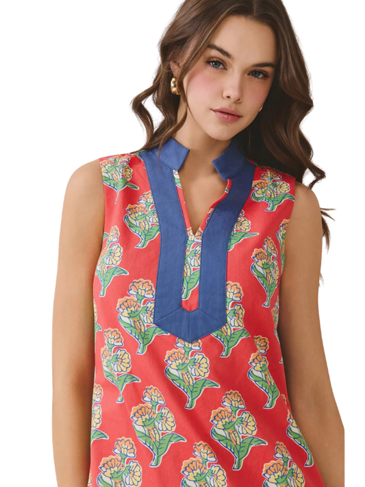 Woman wearing a red floral sleeveless top with blue trim on a white background