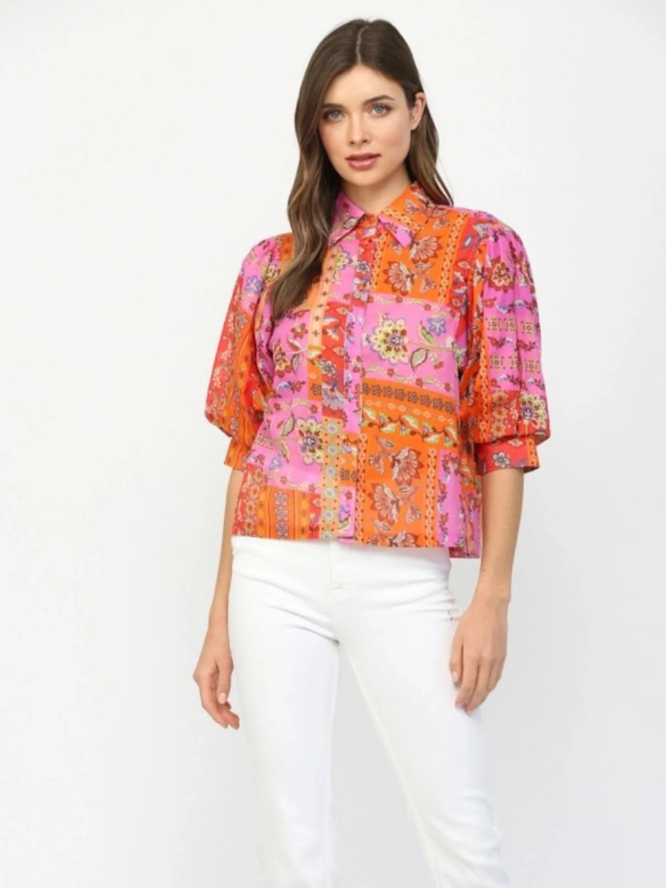 Woman wearing a colorful floral blouse with white pants on a white background