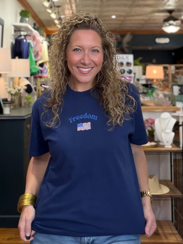 Woman wearing a blue t-shirt with 'Freedom' and an American flag design in a store setting.
