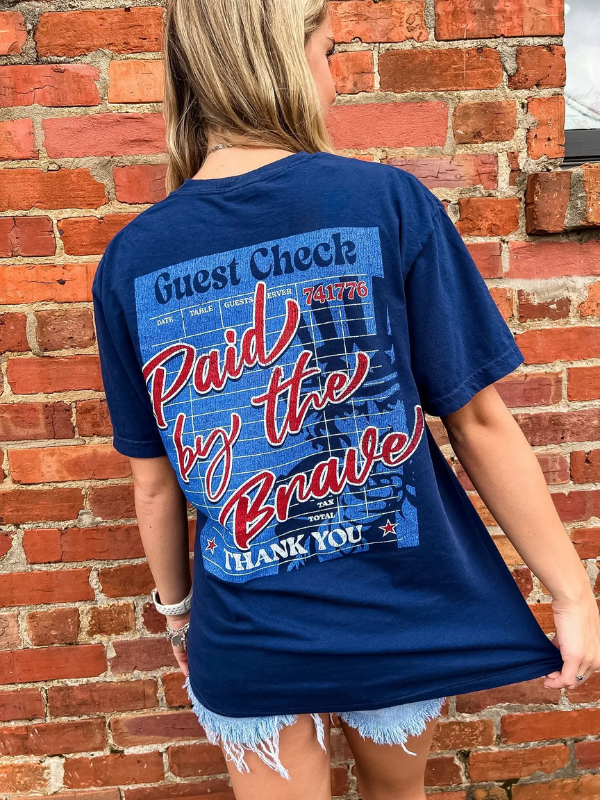 Person wearing a blue t-shirt with text design in front of a brick wall