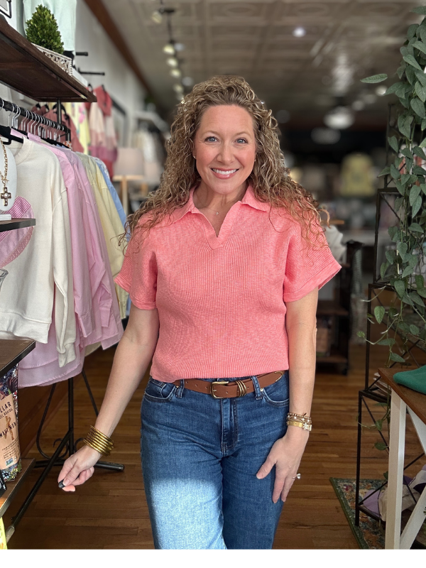 Woman wearing a pink shirt and blue jeans standing in a store.