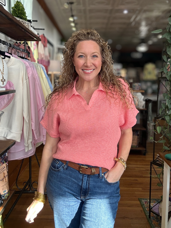 Woman wearing a pink shirt and blue jeans in a store setting