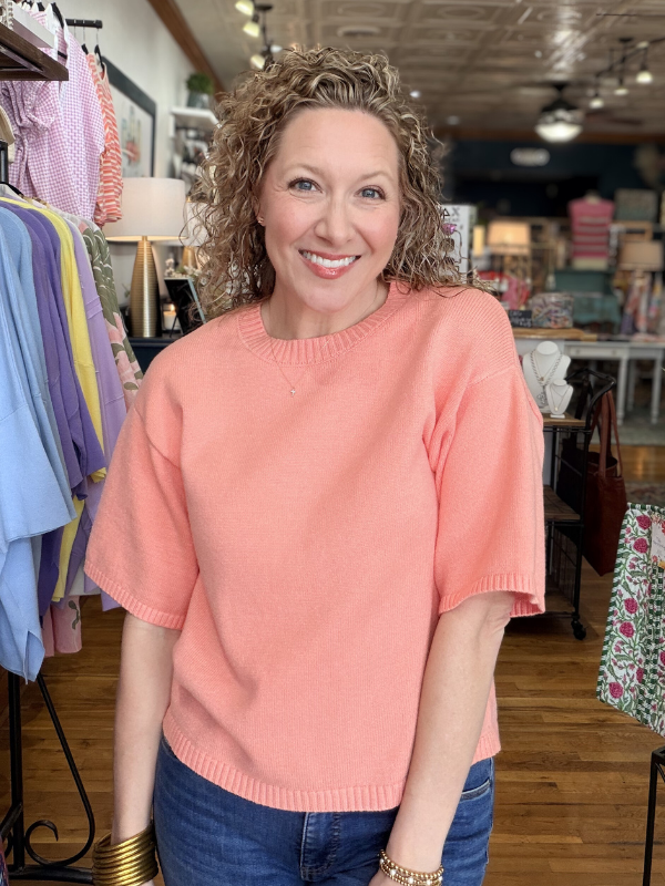 Woman wearing a pink sweater in a store setting
