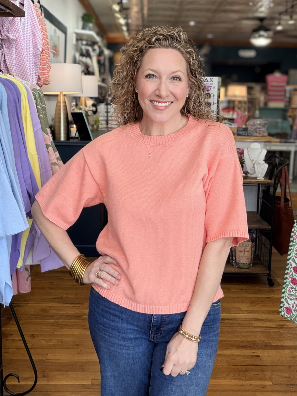 Woman wearing a pink sweater and blue jeans in a store setting