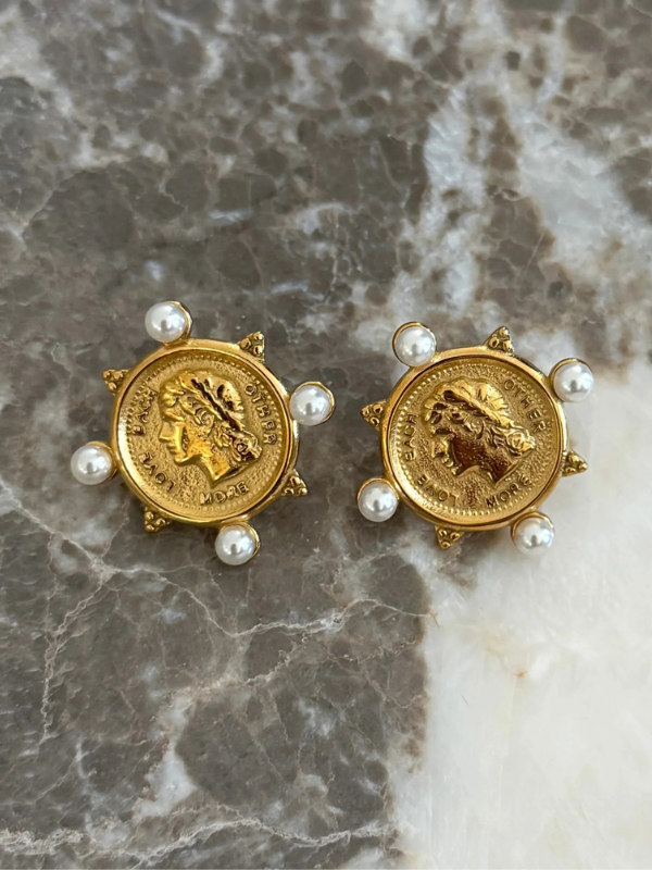 Gold coin earrings with pearls on a marble surface