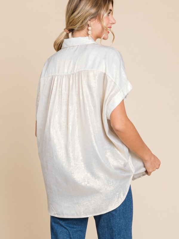 Woman wearing a white blouse with short sleeves against a beige background