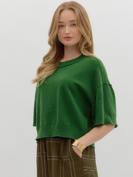 Woman wearing a green sweater against a plain background