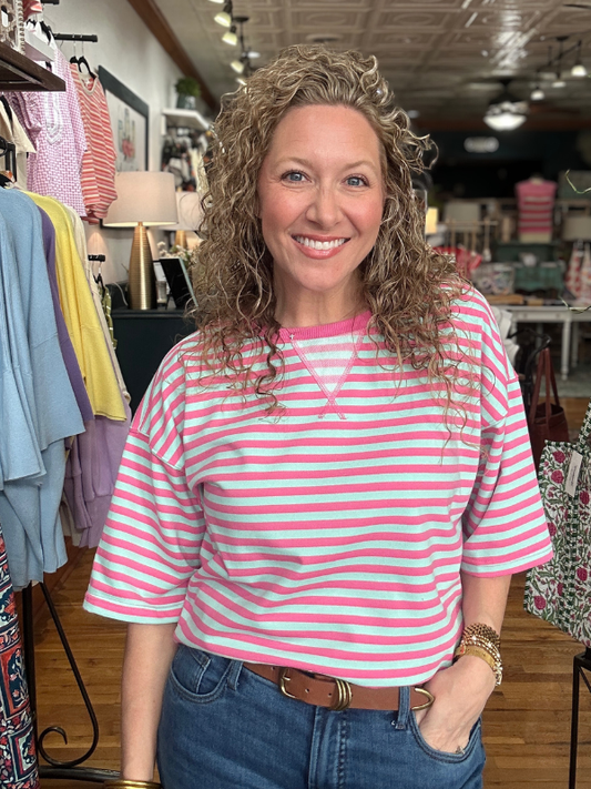 Woman wearing a pink and white striped shirt in a clothing store.