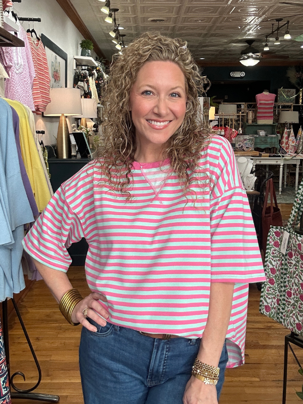 Woman wearing a pink and white striped shirt in a clothing store.