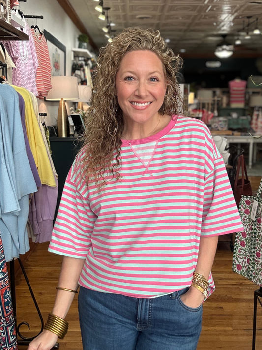 Woman wearing a pink and white striped shirt in a store setting