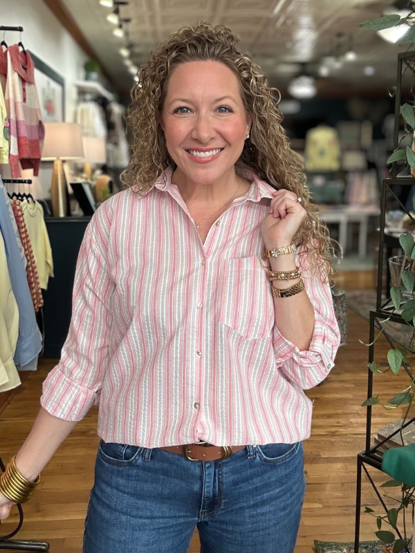 Woman wearing a pink striped shirt and blue jeans in a store setting