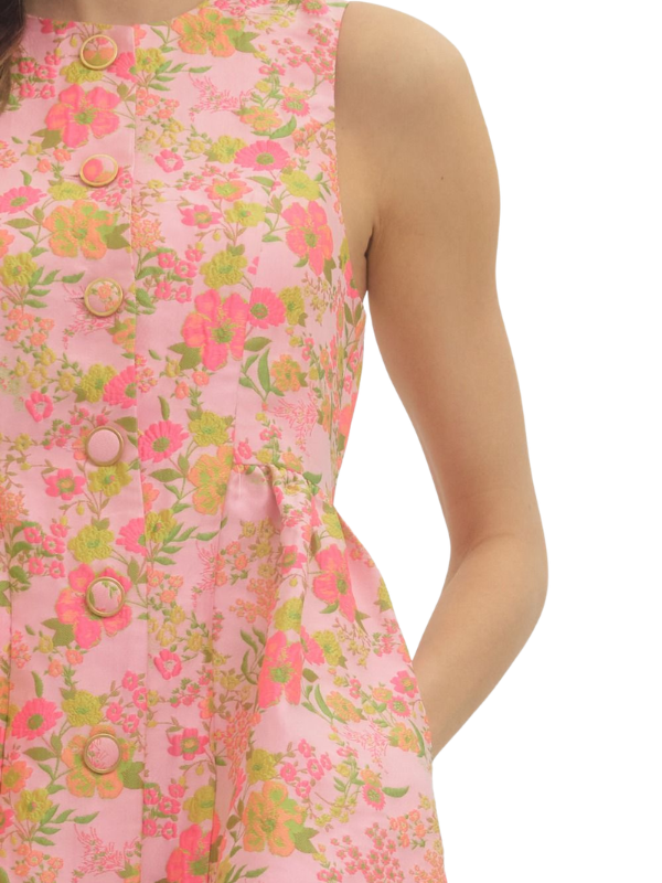 Close-up of a pink floral dress with buttons on a white background
