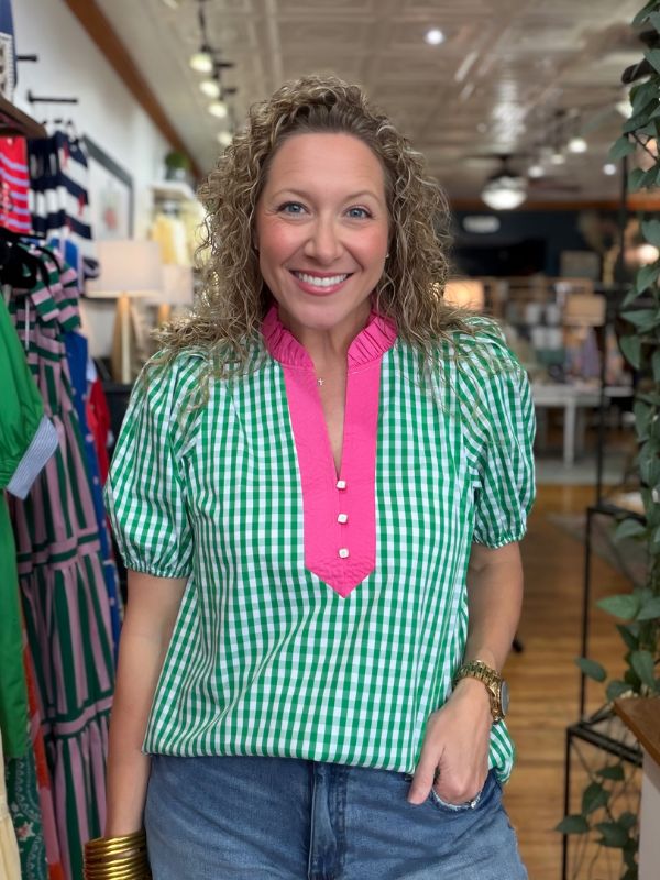 Woman wearing a green and white checkered shirt with pink collar in a store setting
