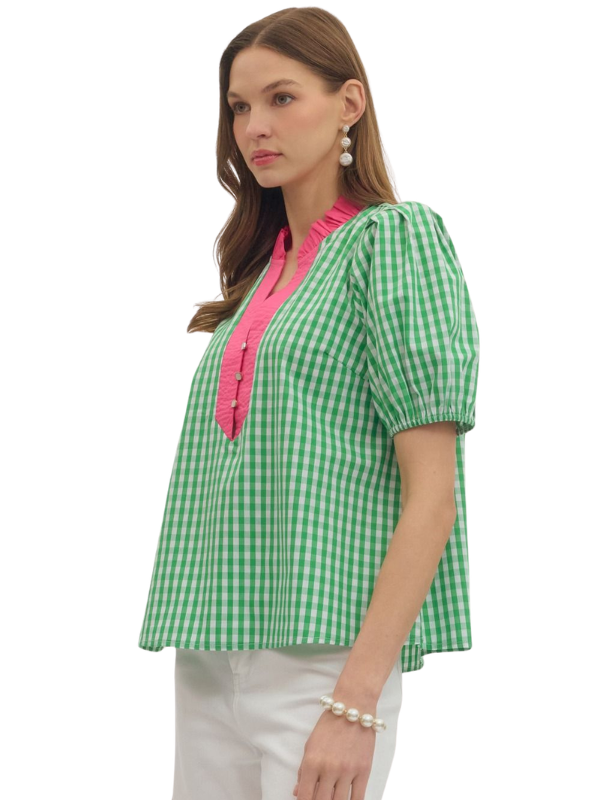 Woman wearing a green and white checkered blouse with pink accents on a white background