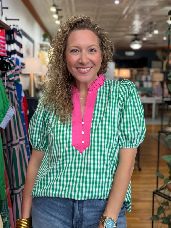 Woman wearing a green and pink checkered blouse in a store setting