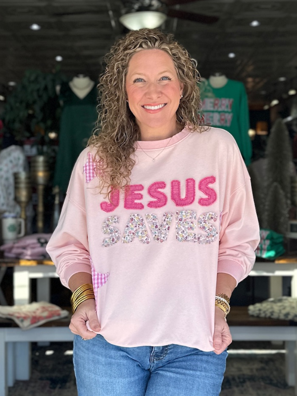 Woman wearing a pink sweatshirt with 'Jesus Saves' text in a store setting