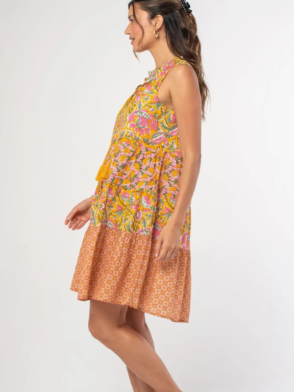 Woman wearing a colorful dress with a floral top and patterned skirt on a white background