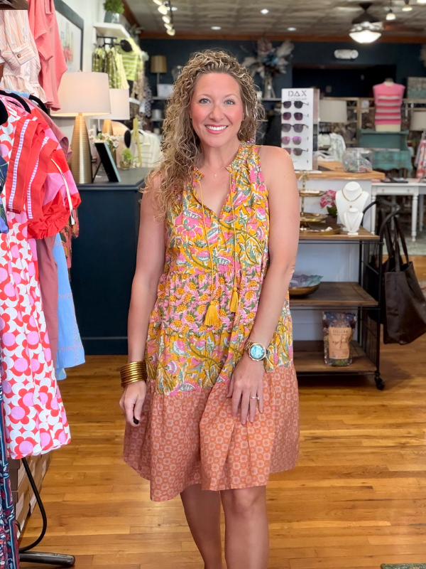 Woman in a colorful dress standing in a store with clothing and accessories around