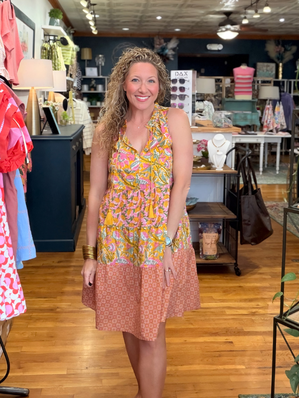 Woman in a colorful dress standing in a store with various items on display.
