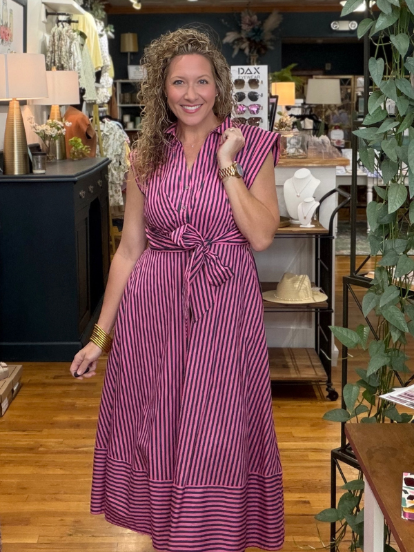 Woman in a striped dress standing in a store with various items in the background