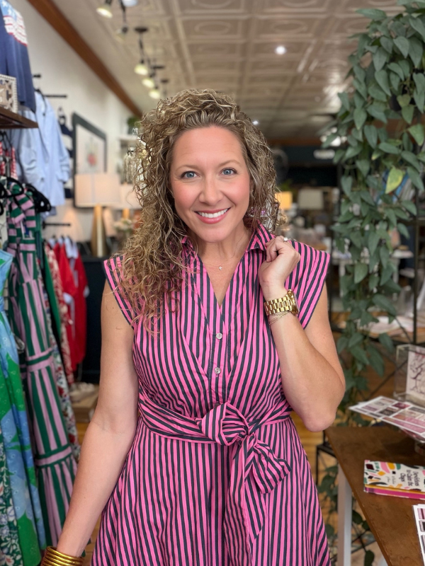 Woman wearing a pink and black striped dress in a store setting