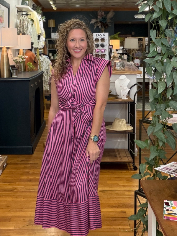 Woman in a purple striped dress standing in a store with shelves and decor in the background.