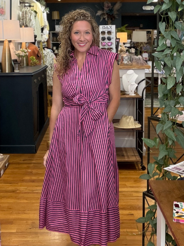Woman in a purple striped dress standing in a store with various items in the background