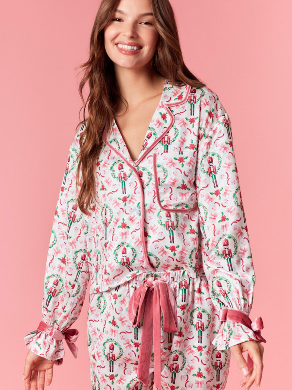 Woman wearing a festive pajama set with candy cane pattern on a pink background